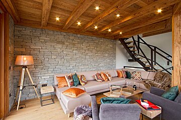 A living room with a sectional couch and stairs