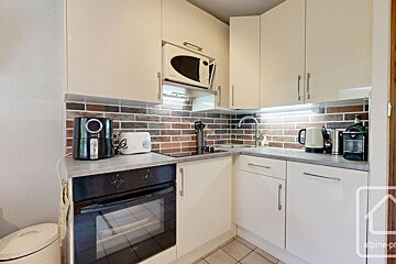 A kitchen with white cabinets and black appliances including a krups coffee maker