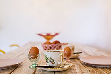 A cup with flowers on it sits on a saucer on a table