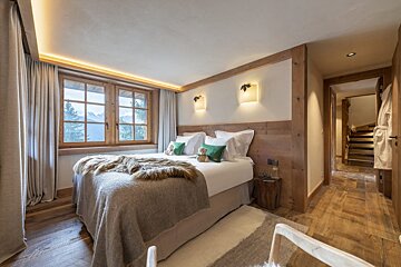 A bedroom with a bed with a teddy bear on it