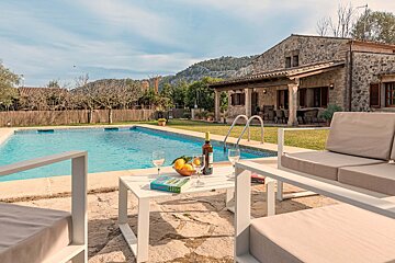 A bottle of wine sits on a table next to a swimming pool