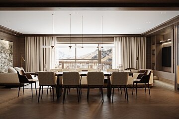 A chic, warm open-plan living/dining room with a large table, modern lighting, wood accents, and a stunning view of snowy mountains through big windows.