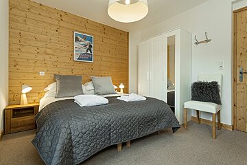 A bedroom with a bed a chair and a poster on the wall that says 