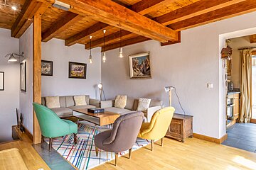A living room with a couch and chairs and a painting on the wall
