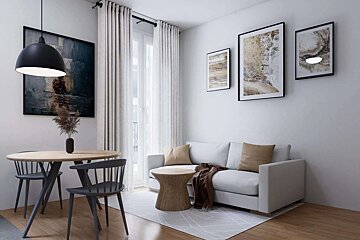 A bright, modern living/dining space featuring a white sofa, round wooden table with dark chairs, abstract art, and light curtains.
