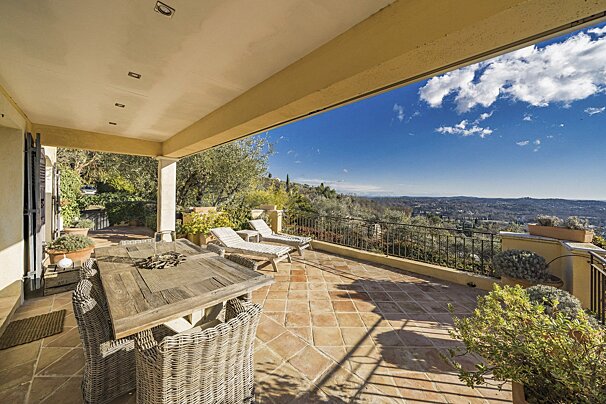 A patio with a table and chairs and a view of the mountains