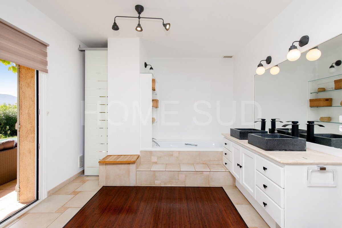 A bathroom with two sinks and a bathtub has the word home on the wall