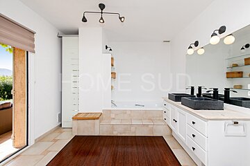 A bathroom with two sinks and a bathtub has the word home on the wall