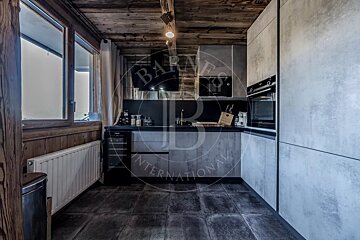 Modern kitchen featuring concrete-look cabinets, dark tiled floor, rustic wooden ceiling, integrated appliances, and a window with a radiator.