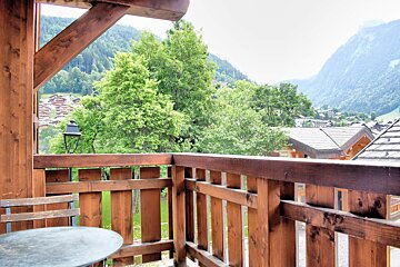 A balcony with a view of mountains and trees