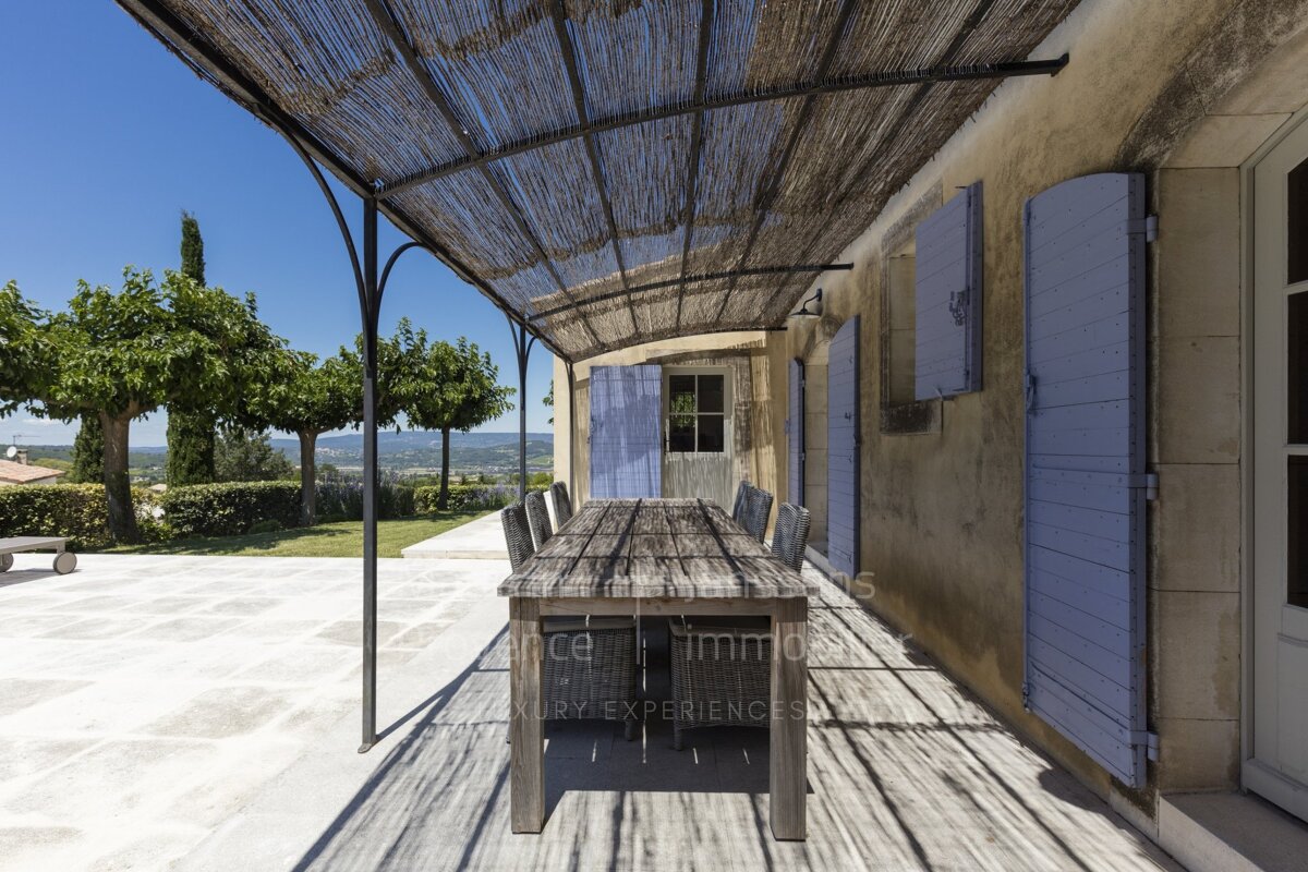 A patio with a table and chairs under a canopy that says france immobiliers