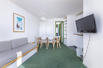 A living room with a table and chairs and a flat screen tv