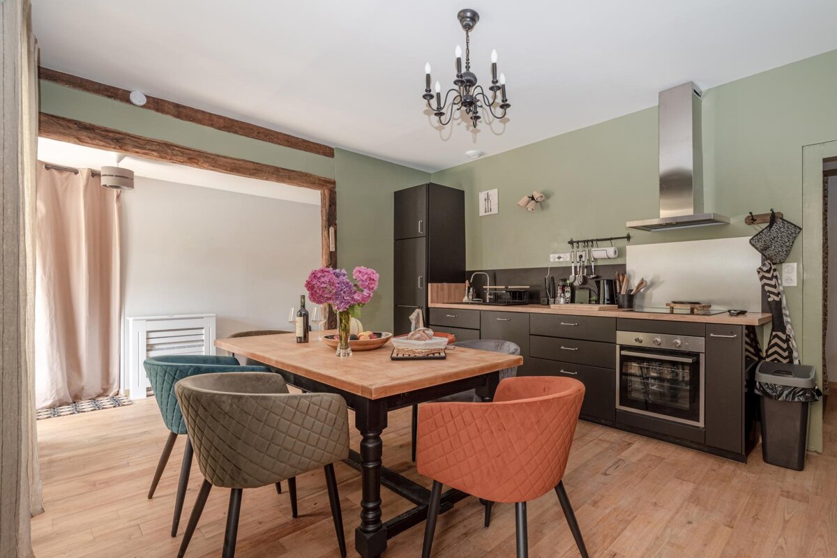 A kitchen with a table and chairs and a vase of flowers on it
