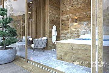 A serene wood-paneled spa room features a bubbling hot tub, cozy seating, and a potted bonsai, opening to nature via a large glass door.