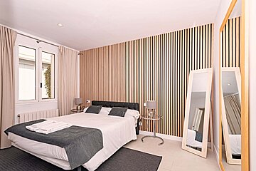 A bedroom with a large bed and two mirrors