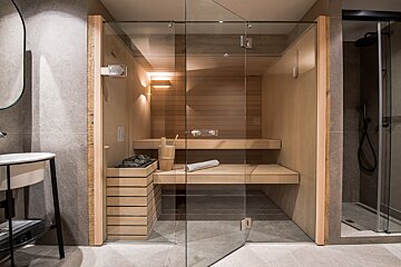 A bathroom with a glass door and a wooden sauna