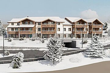 A snow-covered modern alpine chalet complex with wooden balconies, surrounded by snowy pine trees.