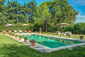 A large swimming pool surrounded by chairs and umbrellas