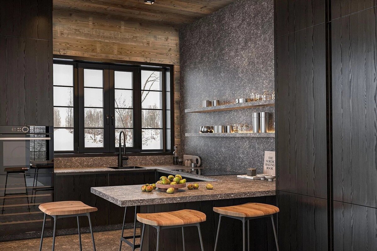 A modern, dark-toned kitchen with a rustic wood ceiling and textured grey walls. A large window overlooks a snowy landscape, complemented by bar stools and fruit.