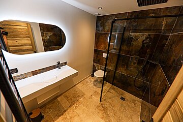 A bathroom with a walk in shower and a sink