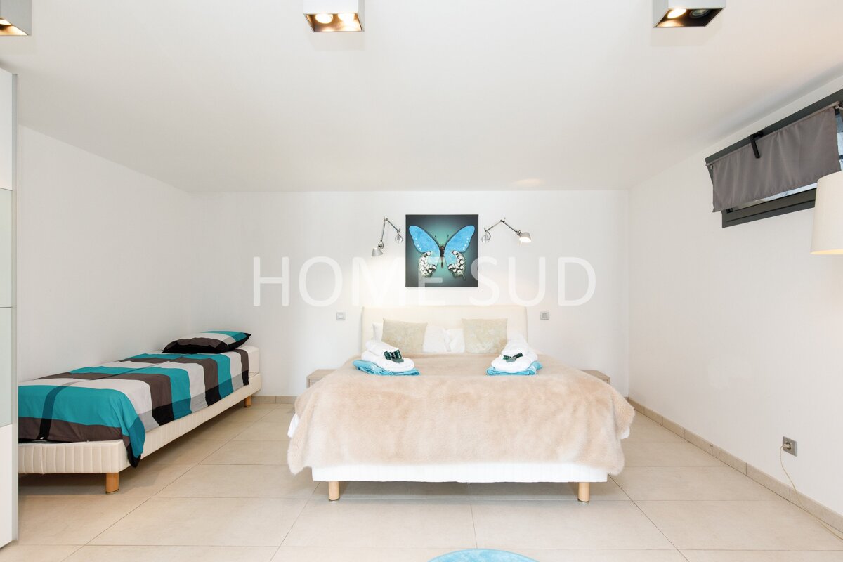 A bedroom with two beds and a painting of a butterfly above the bed