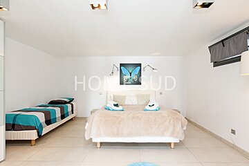 A bedroom with two beds and a painting of a butterfly above the bed