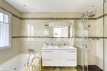 A bathroom with two sinks and a jacuzzi tub says janssens immobilier on the wall