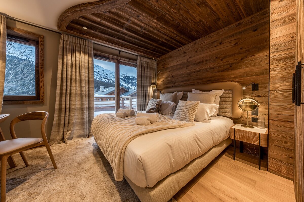 A bedroom with a large bed and a chair