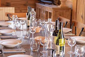 A long table set for a dinner party with bottles of wine and glasses