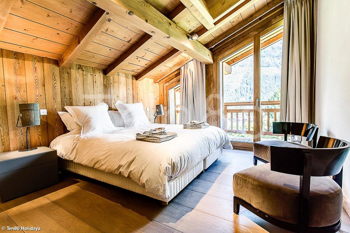 A bedroom with a king size bed and a chair