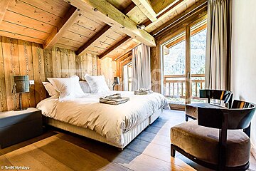 A bedroom with a king size bed and a chair