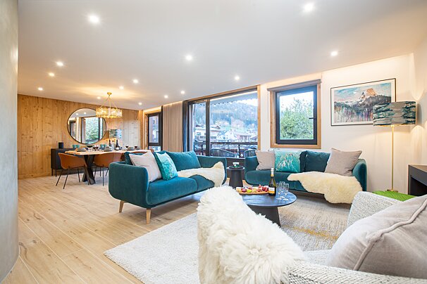 A living room with a blue couch and a white chair