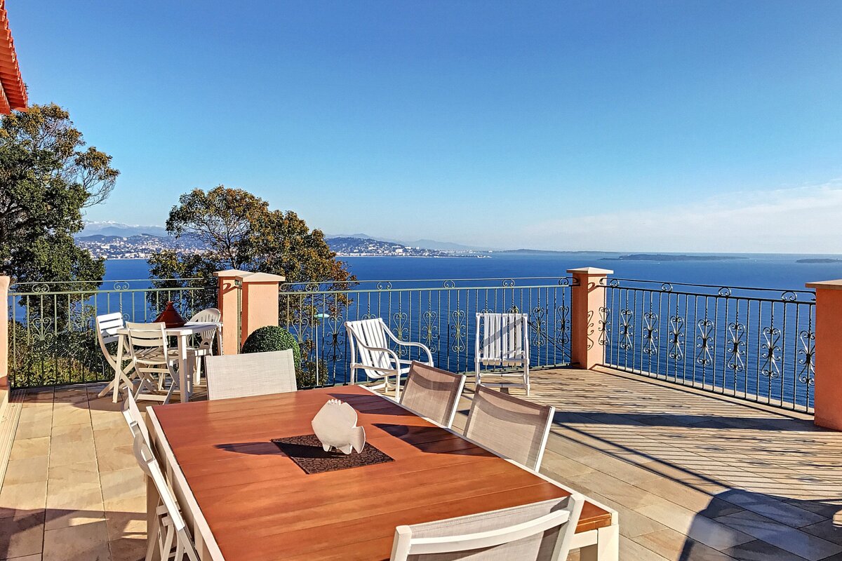 A table and chairs on a balcony overlooking the ocean