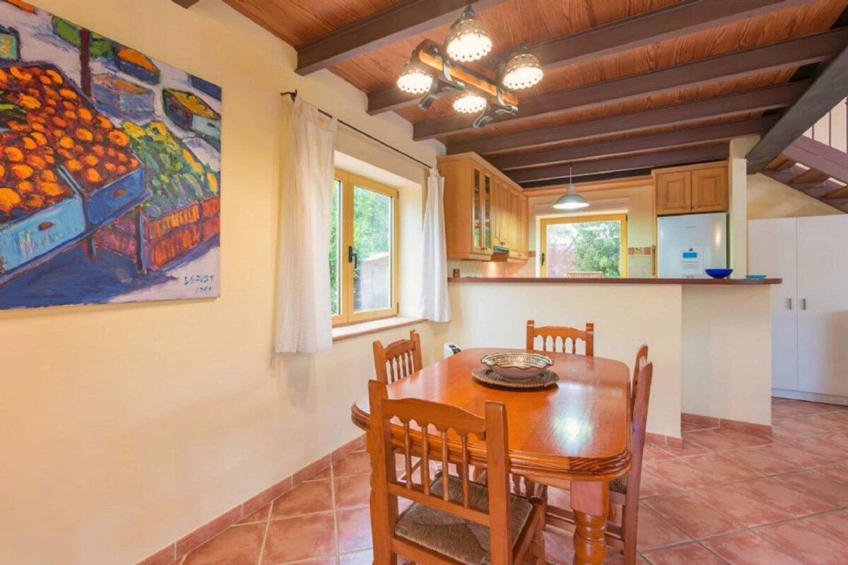 A dining room with a table and chairs and a painting on the wall