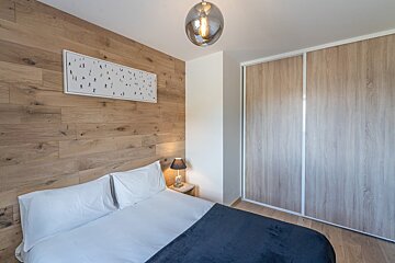 A bedroom with a painting on the wall above the bed