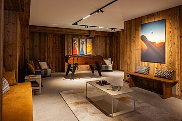 A game room with a table and paintings on the wall