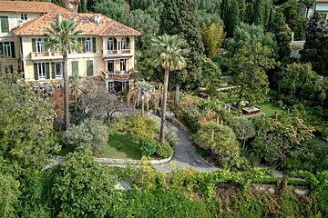 An aerial view of a large house surrounded by palm trees
