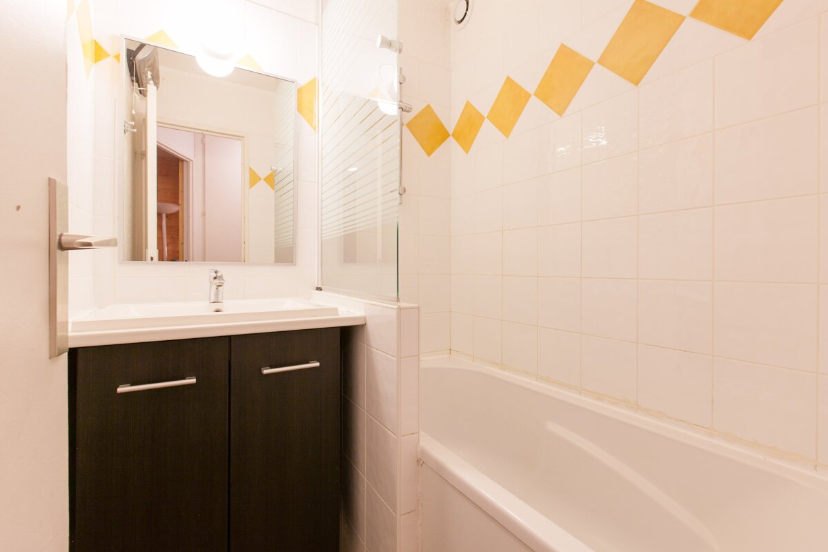 A bathroom with white tiles and yellow squares on the wall