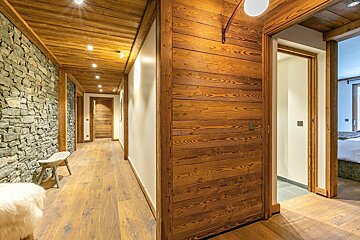 A hallway with wood paneling and a stone wall