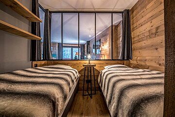 A bedroom with two beds and a glass wall