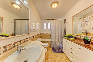 A bathroom with a sink toilet and a large mirror