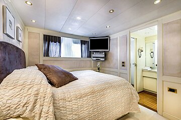 A bedroom with a bed and a television on the wall