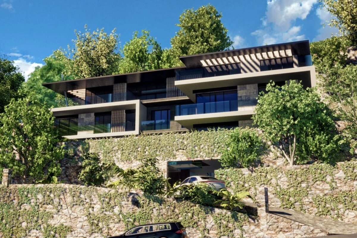 Modern multi-level home built on an ivy-covered hillside, surrounded by lush green trees and stone walls.