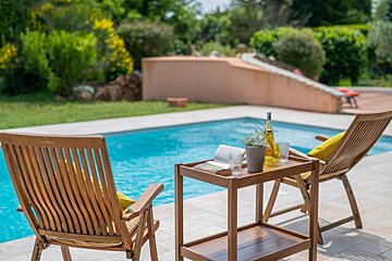 A bottle of wine sits on a table next to two chairs
