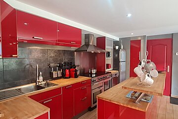 A kitchen with red cabinets and stainless steel appliances