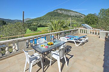 A table and chairs on a balcony with a mountain in the background