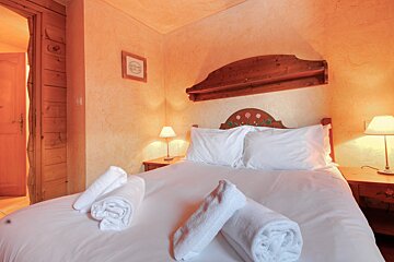 A bedroom with a wooden headboard and white sheets