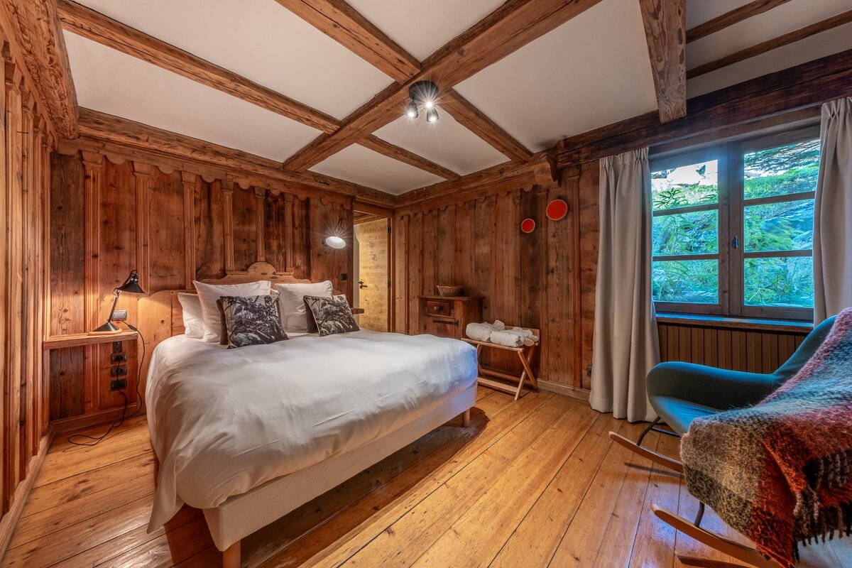 A bedroom with a large bed and a rocking chair