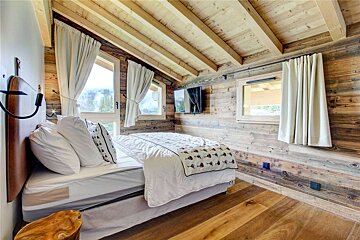 A bedroom with a bed and a television on the wall