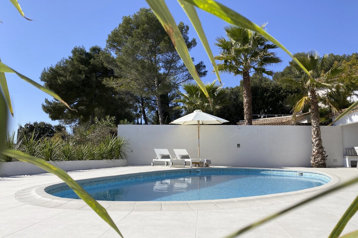 A swimming pool with a white umbrella and chairs